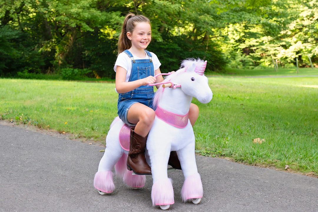 older child riding faster across a lawn, steering with the reins