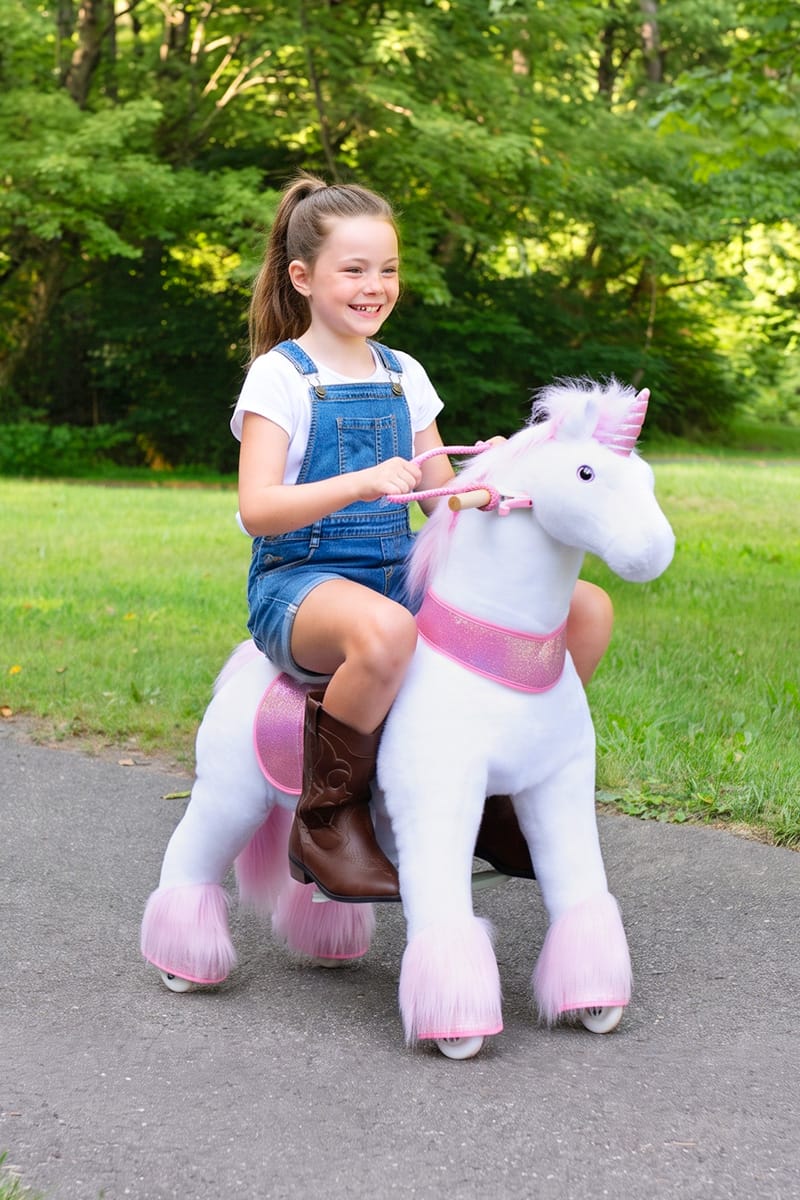 older child riding faster across a lawn, steering with the reins