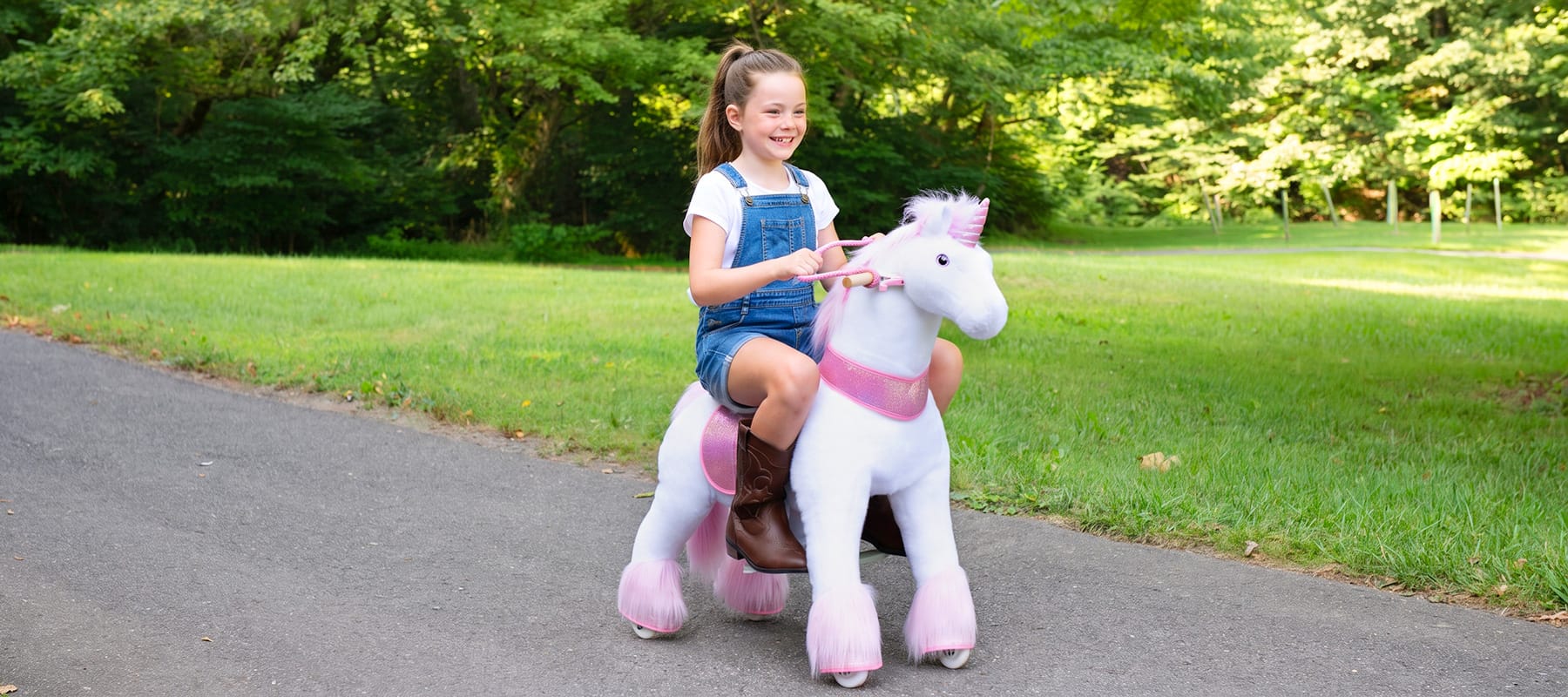 older child riding faster across a lawn, steering with the reins